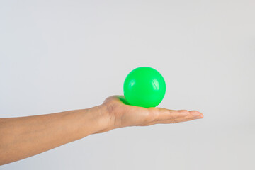 Green plastic ball in hand, white background