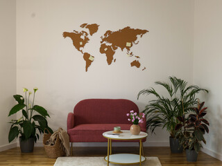 Modern interior with a pink sofa, cork world map wall art, green plants, and stylish decor elements. A warm and inviting living room. © Micha