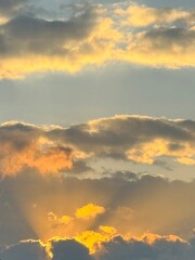 A beautiful evening sky with warm, golden sunlight filtering through dramatic clouds at sunset.
