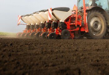 Farmer with tractor seeding in sunset
