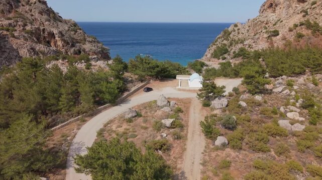 Aerial drone shot following the road to Achata Beach, Karpathos, revealing its turquoise waters, sandy shore, and scenic Mediterranean landscape.