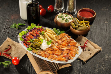 Traditional Turkish Doner Kebab Plate with Fresh Vegetables, French Fries, and Sauces on Rustic Background