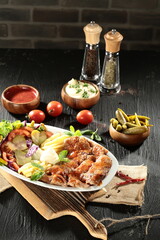 Traditional Turkish Doner Kebab Plate with Fresh Vegetables, French Fries, and Sauces on Rustic Background