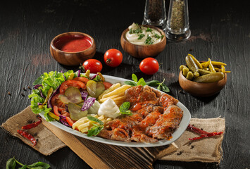 Traditional Turkish Doner Kebab Plate with Fresh Vegetables, French Fries, and Sauces on Rustic Background