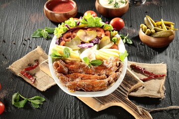Traditional Turkish Doner Kebab Plate with Fresh Vegetables, French Fries, and Sauces on Rustic Background