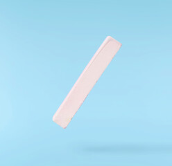 Back to school conception. Flying in the air school equipment. A chalk levitating in the air isolated on blue background