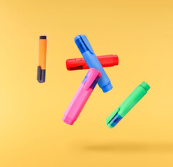 Back to school conception. Flying in the air school equipment. A textmarker   levitating in the air isolated on yellow background