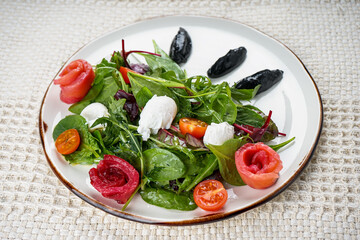 Fresh vegetable salad with salmon and greens in a plate on the background