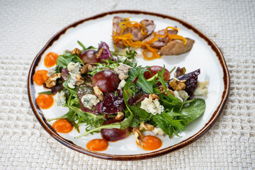 Fresh vegetable salad with veal and greens in a plate on the background