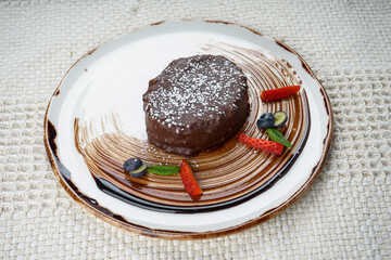 dessert chocolate cake decorated with mint and strawberries in a plate on a background
