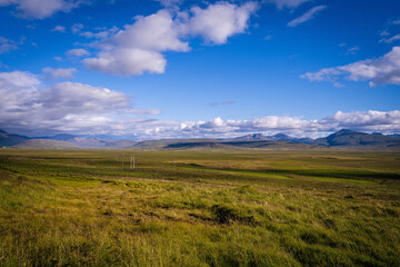Vast green plains stretch beneath Iceland’s open skies where distant mountains rise on the horizon in a scene of pure untouched wilderness