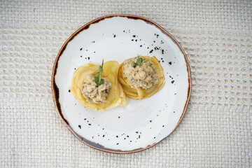 Pancakes with meat filling and microgreens in a plate on a white background