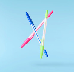 Back to school conception. Flying in the air school equipment. A pen levitating in the air isolated on blue background
