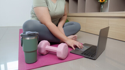Home Fitness. Woman using laptop for online workout with dumbbell.