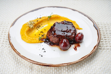 meat in plum sauce with mousse on a plate