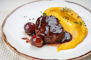 meat in plum sauce with mousse in a plate on a white background macro
