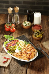 "Traditional Turkish Doner Kebab Plate with Fresh Vegetables, French Fries, and Sauces on Rustic Background"