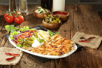 "Traditional Turkish Doner Kebab Plate with Fresh Vegetables, French Fries, and Sauces on Rustic Background"