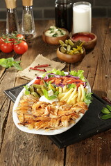 "Traditional Turkish Doner Kebab Plate with Fresh Vegetables, French Fries, and Sauces on Rustic Background"