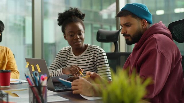 Multi-Ethnic entrepreneurs of informal business startup in office meeting diverse team work process in company workgroup, African American woman talk with Indian Arabian man strategy session planning