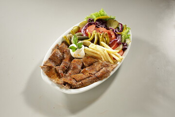 Traditional Turkish Chicken Doner Kebab Plate with French Fries, Pickles and Fresh Vegetables on white background
