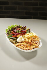 Traditional Turkish Chicken Doner Kebab Plate with French Fries, Pickles and Fresh Vegetables on white background
