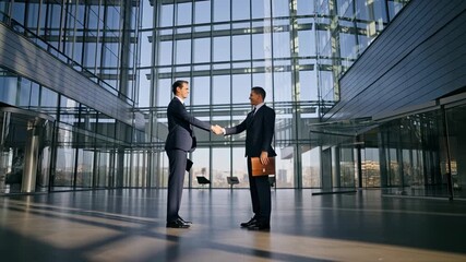 Two diverse businessmen shake hands modern glass building lobby closing a deal this corporate scene symbolizes success partnership agreement negotiation teamwork professional greeting meeting welcome - Powered by Adobe