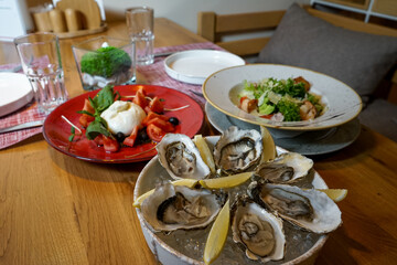 a plate of oysters and lemons on a table with other dishes