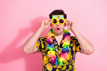 Colorful man wearing tropical shirt and pineapple glasses posing on a pink background celebrating summer fun.