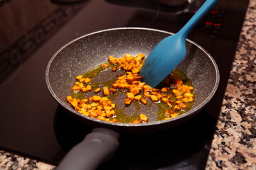 Fresh chopped carrots cooking on frying pan on induction stove. Cooking delicious dish with vegetables at home.