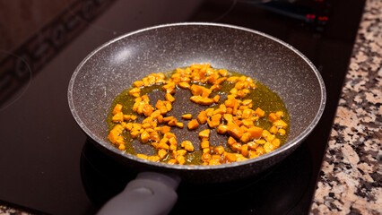 Fresh chopped carrots cooking on frying pan on induction stove. Cooking delicious dish with vegetables at home.