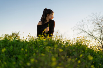 Young woman holding wildflower enjoying sunset in meadow