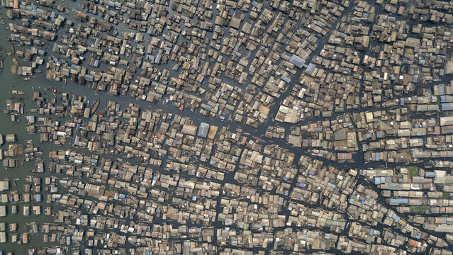Aerial view of tightly packed buildings on water, creating a dense, textured tapestry of contrasting light and shadow, Makoko, Lagos, Nigeria.