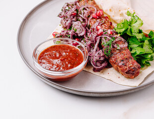 Savory skewer with onion salad and sauce served on flatbread