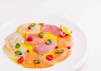 Colorful seafood platter with assorted fish and garnishes on white plate