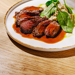 Delicious grilled meat served with creamy sauce and fresh spinach on a plate