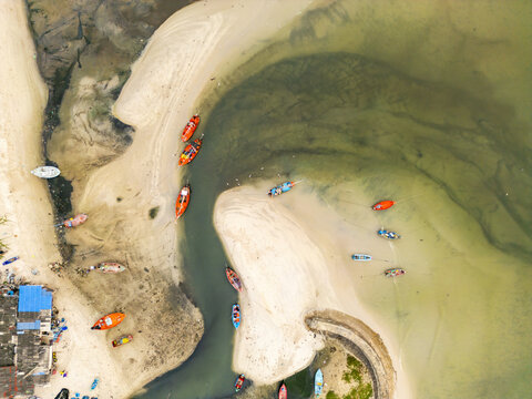 Aerial view of boats resting on the shore with golden sands blending into turquoise waters, Hua Hin, Prachuap Khiri Khan, Thailand.