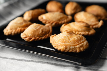 Crispy curry puffs on black tray with selective focus