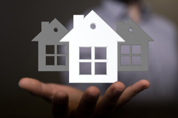 Image of a real estate agent's hand holding digital house models, symbolizing home ownership and property investment.