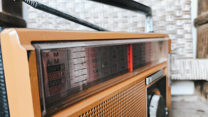 Fototapeta premium Old-fashioned vintage radio resting against a traditional woven rattan background. Perfect for retro interior, antique lifestyle, cultural heritage, and nostalgic design composition themes.