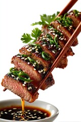 Sliced grilled meat, drizzled with sauce, on chopsticks