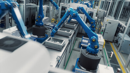 Autonomous Factory with Blue Robot Hands Efficiently Assembling Components on a Production Line, Showcasing Advanced Automation and Precision Engineering in a Modern Manufacturing Plant. High Angle