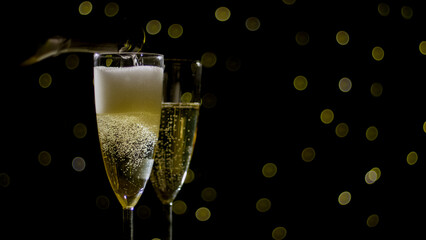 Two champagne flutes filled with bubbly shine against a backdrop of soft glowing lights, evoking...