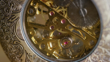 Close-up view of a pocket watch mechanism showcasing its intricate gears and craftsmanship during daylight.