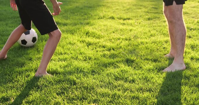 Father and son playing football captures joy and family bonding. Dad and child playing soccer barefoot outdoors feels natural. Father and boy playing highlights summer freedom. Ball and legs close-up. - Powered by Adobe