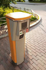 Entry stand for parking equipment on a city street on paving slabs. Daytime, sunny day.