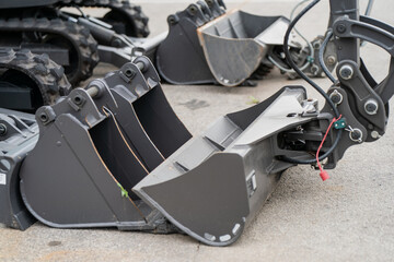 Metal excavator bucket attachments placed on ground, versatile digging tools used in construction, demolition, soil excavation, mining and heavy equipment operations with hydraulic systems