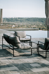 Fototapeta premium Comfortable outdoor seating area overlooking a scenic landscape near a swimming pool