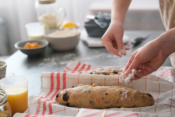 Hands formed loaves of Christmas Bread or stollen cake are arranged on a table in a kitchen. A...