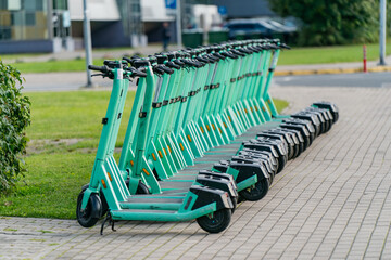 Row of green electric scooters parked on city sidewalk showing modern urban mobility infrastructure, shared transportation system and eco-friendly commuting solution in contemporary environment © K